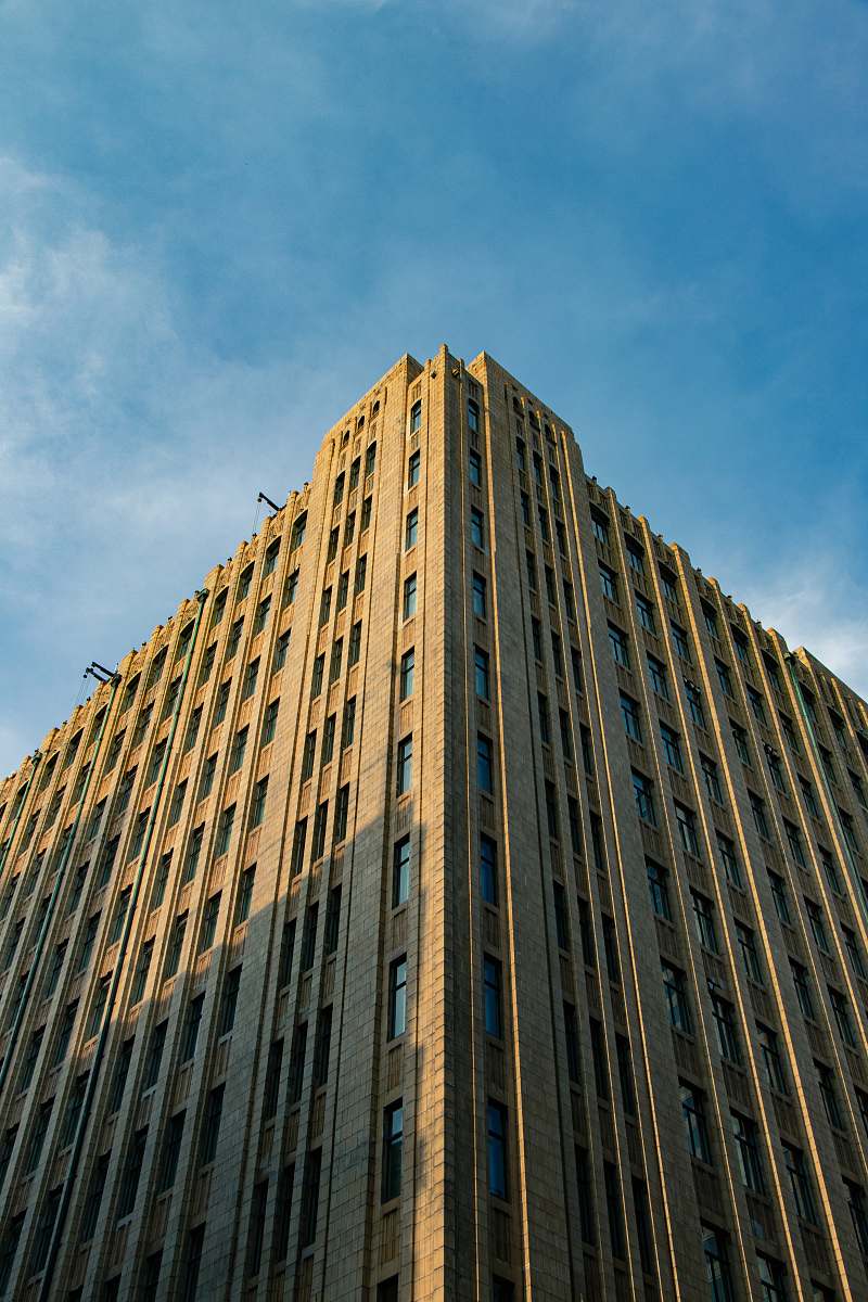 corner low-angle photography of brown high-rise building under a calm blue sky condo